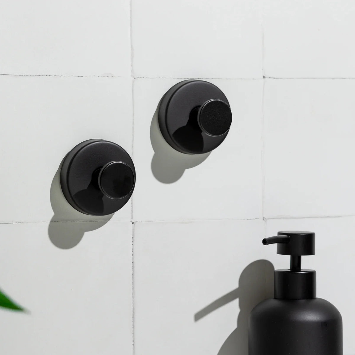Black Mountly hooks with a towel on bathroom tiles